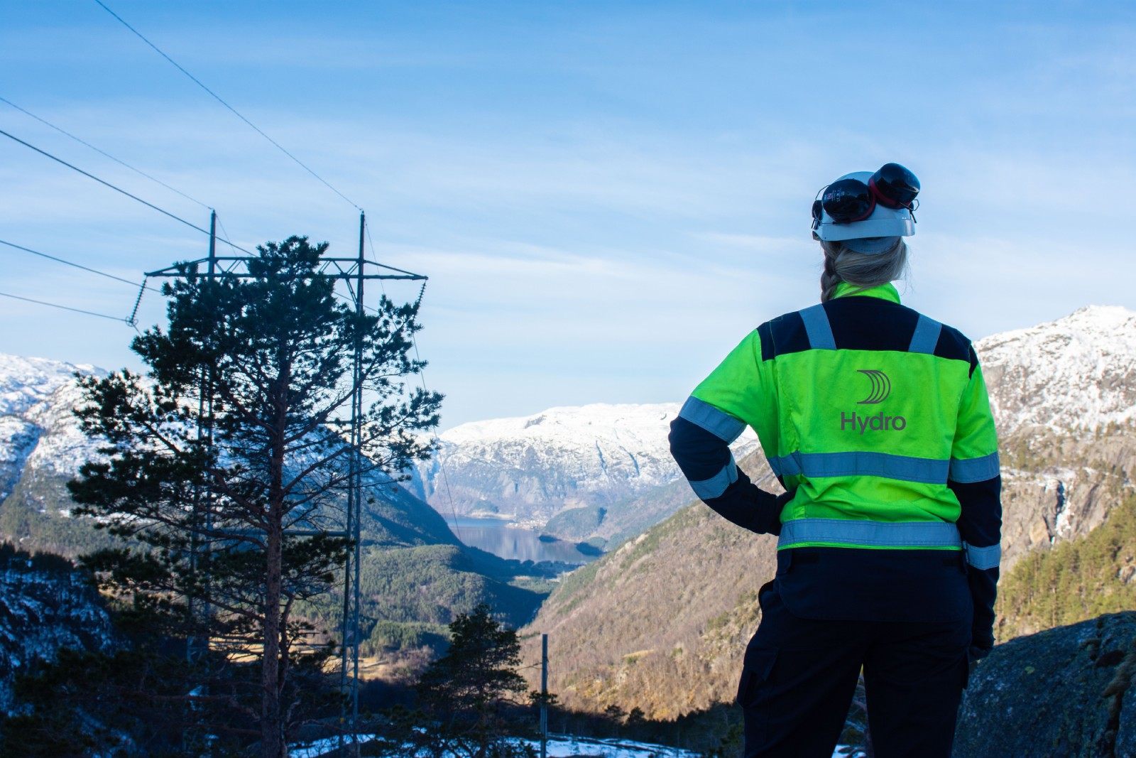Worker in Hydro gear, looking out over mountainous winter landscape