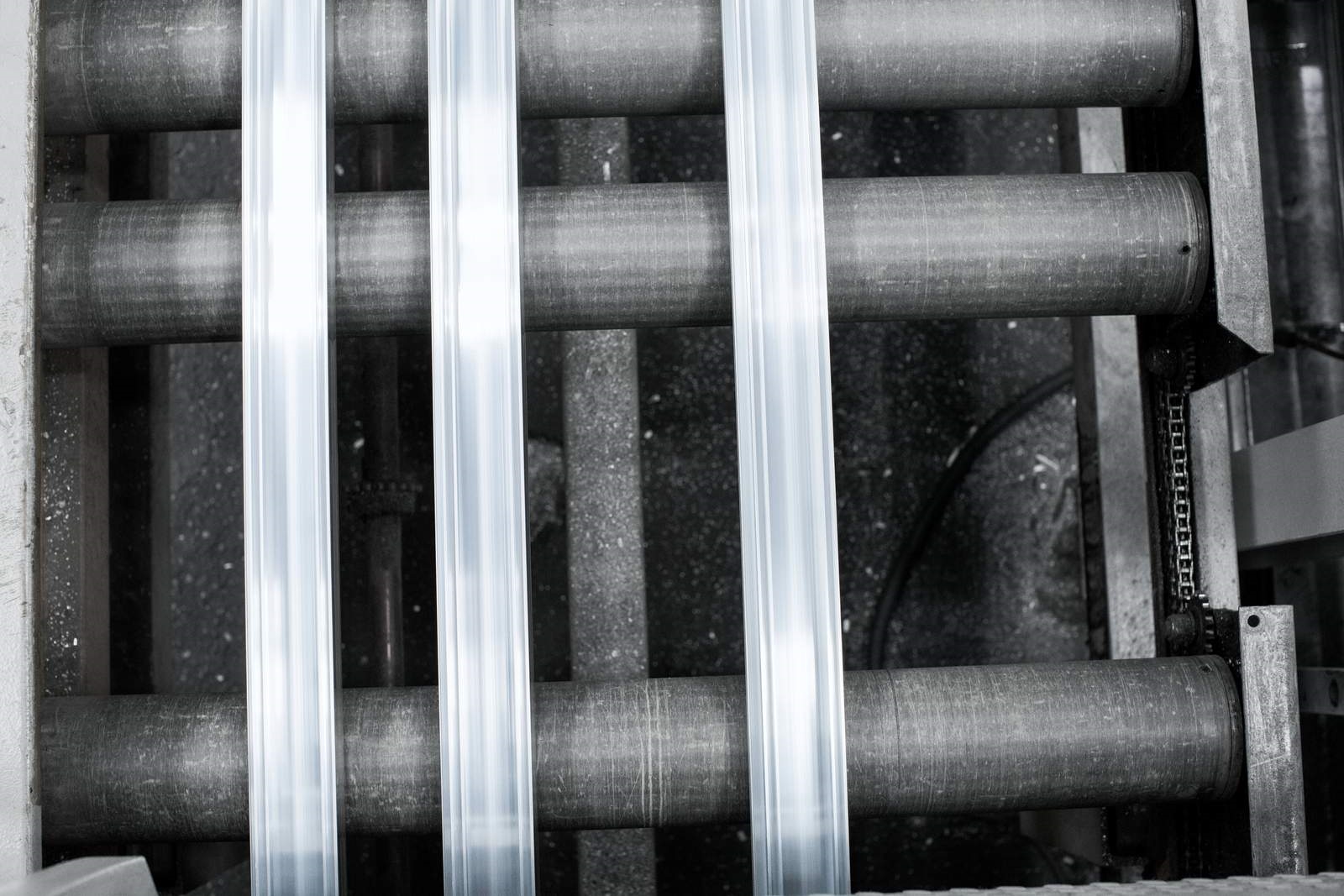 Overhead image of three pieces of extruded aluminum on rollers