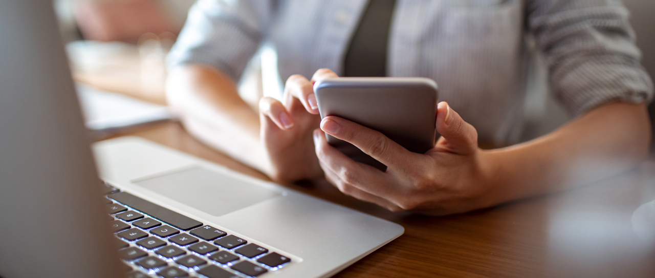 Jemand, der ein Aluminium-Smartphone und einen Laptop verwendet